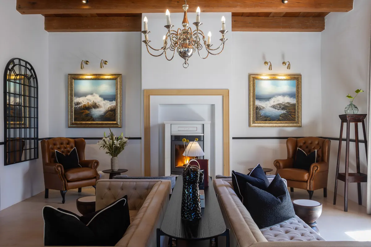 A guesthouse lounge with a chandelier, an open fire and leather armchairs