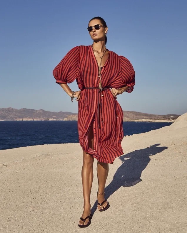 A woman in a Sea Level striped kaftan on the shore